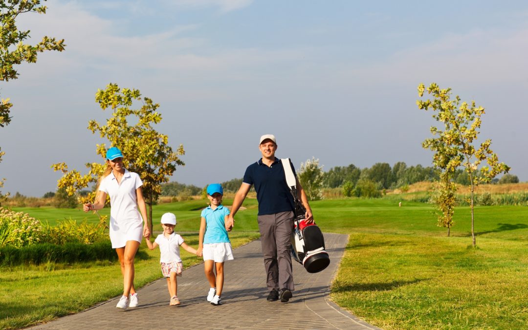Family of golfers walking down golf course path.